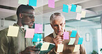 Mature man, board and sticky note with team, review and brainstorming for project at media company. Business people, glass wall and writing for feedback, planning or collaboration at creative agency
