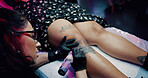 Tattoo, body art and artist or woman with leg in store for permanent ink, linework design and aesthetic. Culture, self expression and tattooing parlor with person and customer in studio for identity