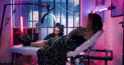 Buy stock photo Tattoo, artist and neon with women in store for permanent ink, linework design or aesthetic. Culture, self expression and tattooing parlor with person and customer in studio for identity and body art
