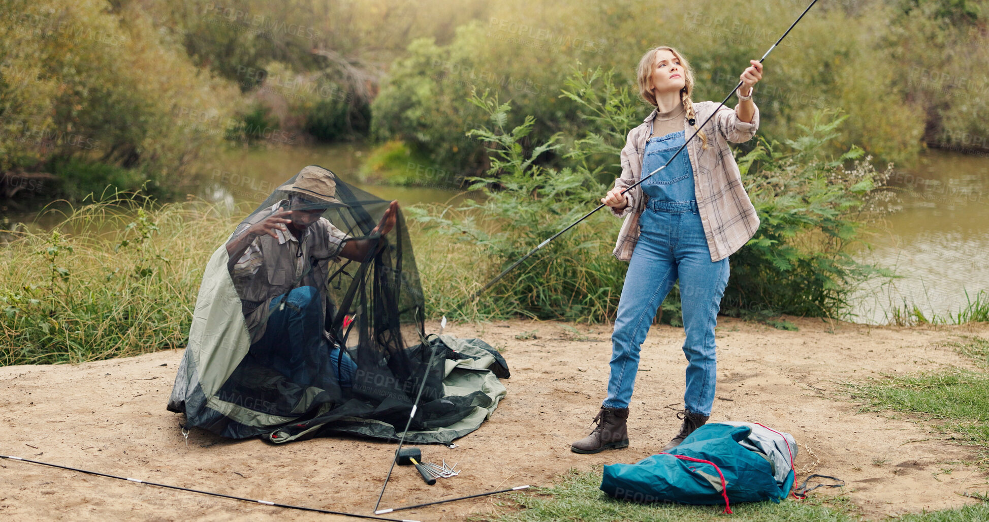 Buy stock photo Couple, pitching and tent for camping outdoor for travel gear, vacation adventure and bonding together. People, helping and setup equipment as nature shelter, campsite preparation and holiday getaway