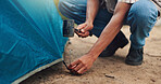 Camping, hands of man and tent with hammer for gear security, holiday adventure or preparation. Countryside, travel and person assemble shelter at campsite for weekend vacation, survival and safety