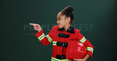Buy stock photo Happy girl, firefighter and pointing with helmet in studio for career day on a green background. Child, kid or smile with costume or outfit for advertising or marketing safety tips on mockup space