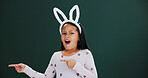 Bunny ears, pointing and portrait with girl child in studio for announcement or notification. Easter, promotion and space with surprised kid isolated on green background for wow gesture or reaction