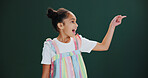 Studio, announcement and child with smile, pointing and happy for presentation, news or mockup space. Green background, advertising and girl with positive attitude for offer alert, deal and promotion