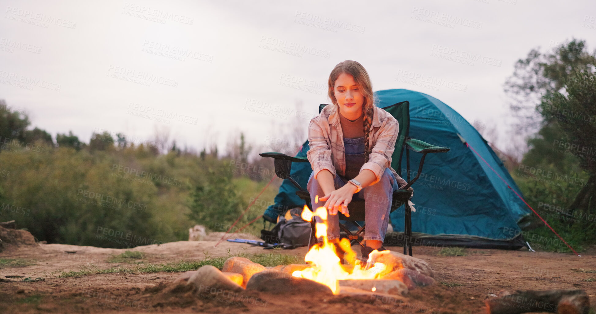 Buy stock photo Camping, woman and relax by fire in nature for warmth, heating hands or holiday adventure. Countryside, travel and person with burning firewood for peaceful vacation, eco friendly comfort and space