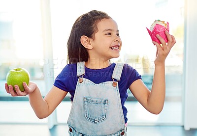 Buy stock photo Smile, choice and girl with fruit, dessert and eating of healthy, food and growth of development of child. Kitchen, decision and kid with apple, cupcake and thinking of nutrition or cake in house