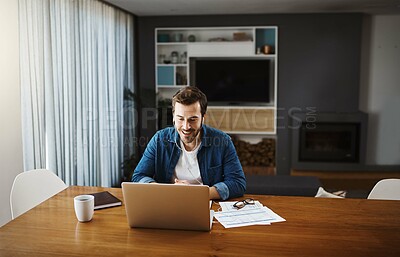 Buy stock photo Shot of a handsome young businessman sitting down and using his laptop to take a video call while working from home
