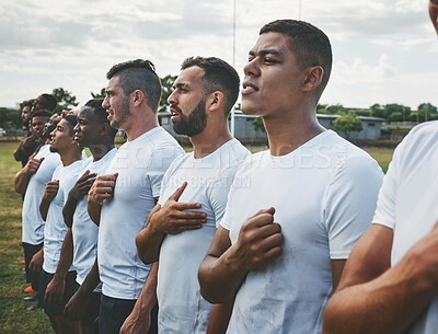 Buy stock photo Cropped shot of a team of confident young rugby players standing at attention singing their anthem outside on a field before a rugby match