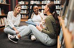 Education, students or women friends in library floor for comic conversation, learning or book study. Diversity, happy or girl with smile for university support, college research or school project