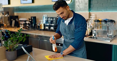 Buy stock photo Waiter, man and cleaning table in cafe for dust, bacteria and dirt with cloth, spray or detergent. Barista, person or wipe wooden furniture in coffee shop or restaurant with chemical liquid for shine