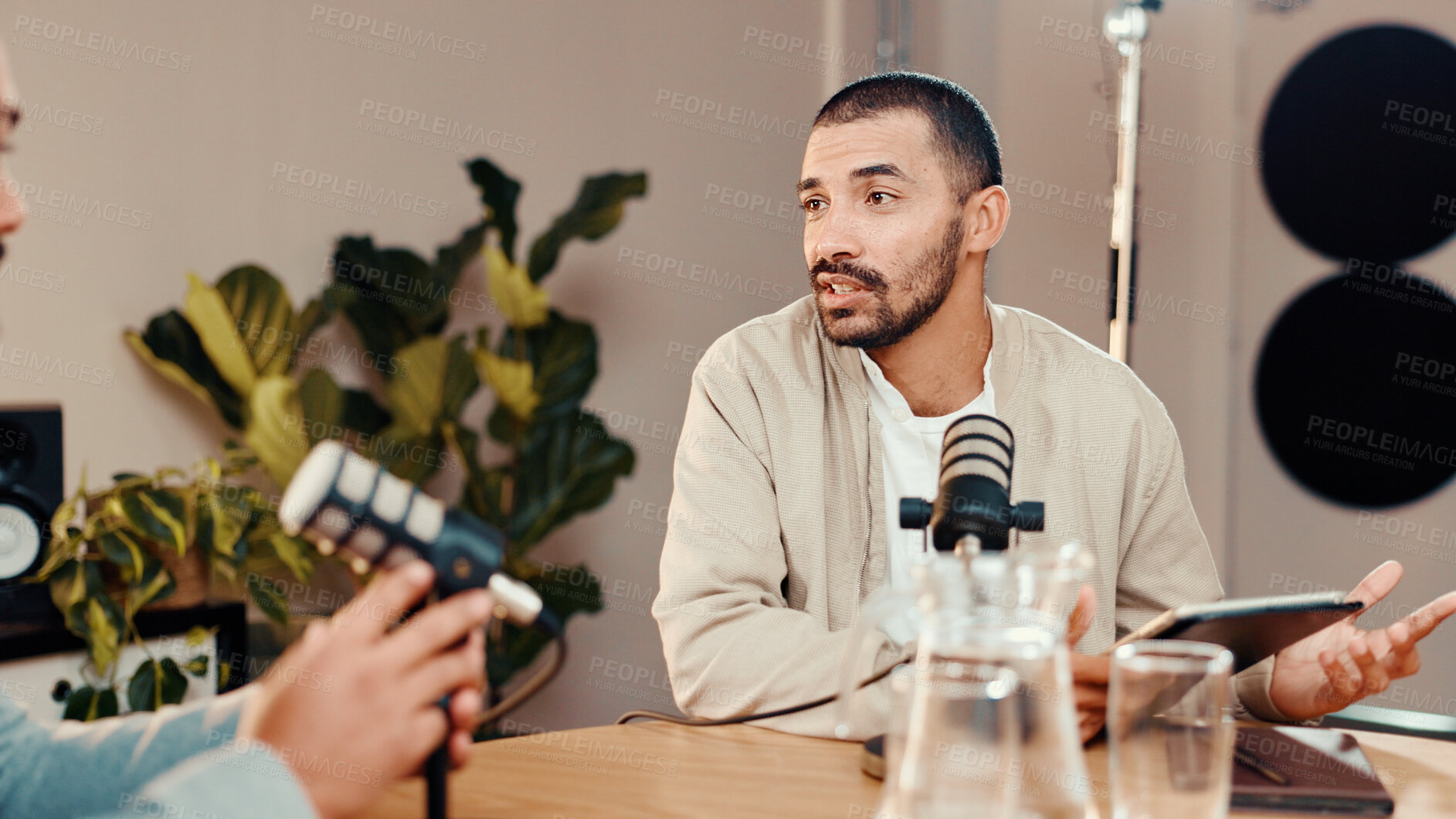 Buy stock photo Podcast, mic and man with guest in studio for interview, conversation and broadcast for radio show. Content creation, hosting and presenter with person on tablet for recording, live stream or talking