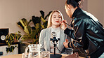 Makeup brush, beautician and presenter in recording studio for podcast, getting ready or online show. Live stream, radio broadcasting or woman with cosmetics for host, content creation and microphone