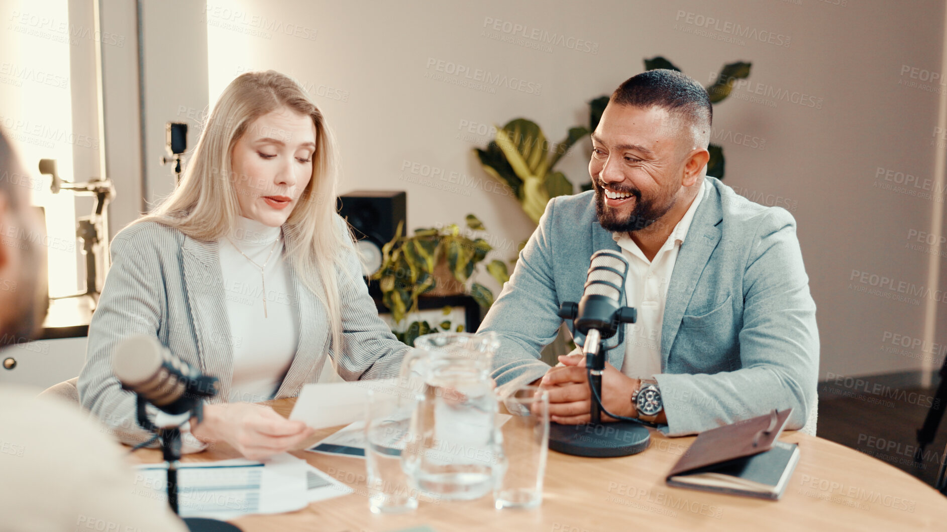 Buy stock photo Podcast, people and talk with paperwork in studio, business show and reading economy review. Document, happy podcaster and recording audio with mic, panel and live stream for entrepreneur advice