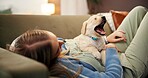 Woman, relax and playing with dog on sofa for puppy love, animal welfare or care in home. Female person, pet owner or labrador lying on couch with yawn for comfort, safety or security in house
