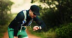 Fitness, nature and man on break with running, workout or training for marathon outdoor. Tired, breathing and male athlete with watch for cardio exercise in forest for race practice with rest.