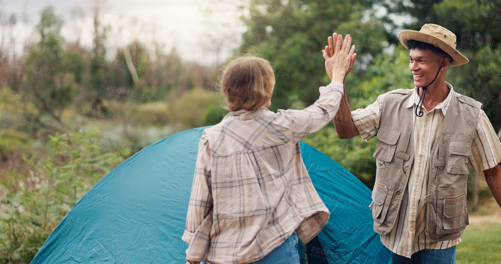 Buy stock photo Couple, camping and high five by tent, excited and smile for achievement, goals or holiday in nature. People, man and woman in woods with interracial love, celebration and pitch shelter for vacation.