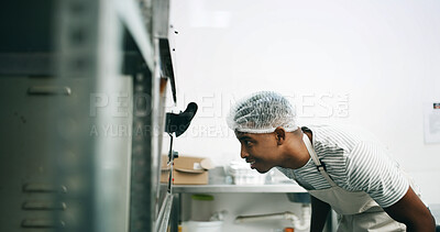 Buy stock photo Baker, kitchen and black man at oven for check, cooking or control temperature for food preparation. Professional chef, safety regulations or person watch baking in restaurant, observe and ready time