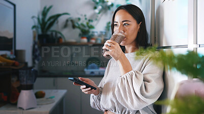 Buy stock photo Woman, phone and drink smoothie in kitchen, glass and gut health with texting for web chat in home. Person, smartphone and thinking with mobile app, contact or social media with nutrition in house