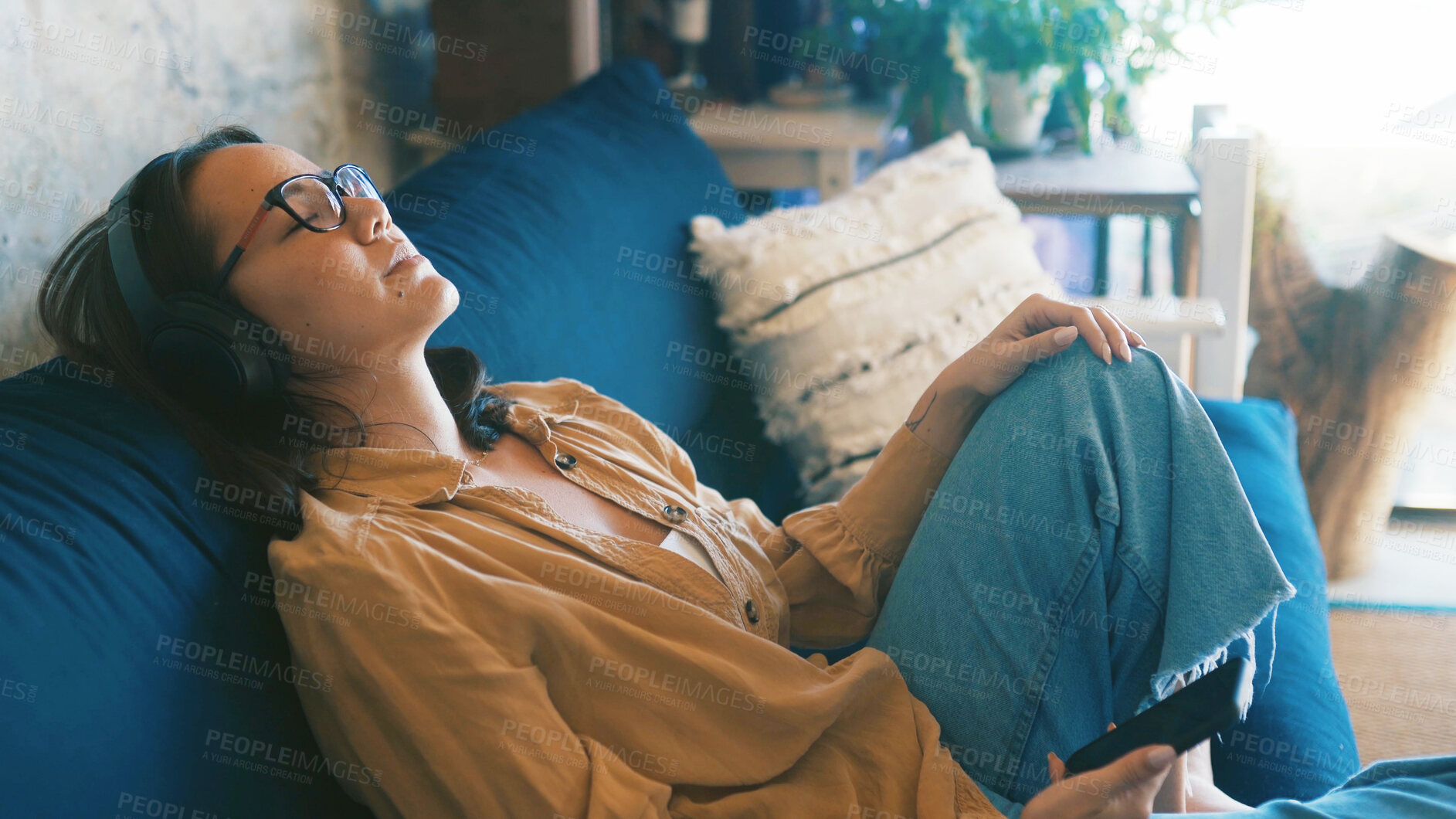 Buy stock photo Lounge, smartphone and woman with headphones, rest and listen to music with subscription and online. Streaming, audio and person with mobile for song selection, relax and calm with tech in house