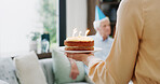 Home, birthday cake and couple in lounge, candles and celebration with surprise. Apartment, relationship and man with woman, sweet food and happiness with marriage, snack and love with dessert