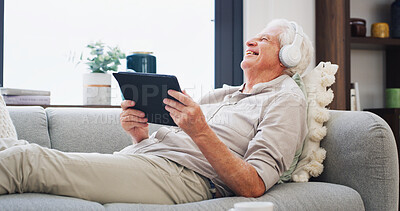 Buy stock photo Laughing, music and tablet with old man on sofa in living room of home for subscription streaming. App, funny and headphones with happy senior person in apartment for audio or sound entertainment