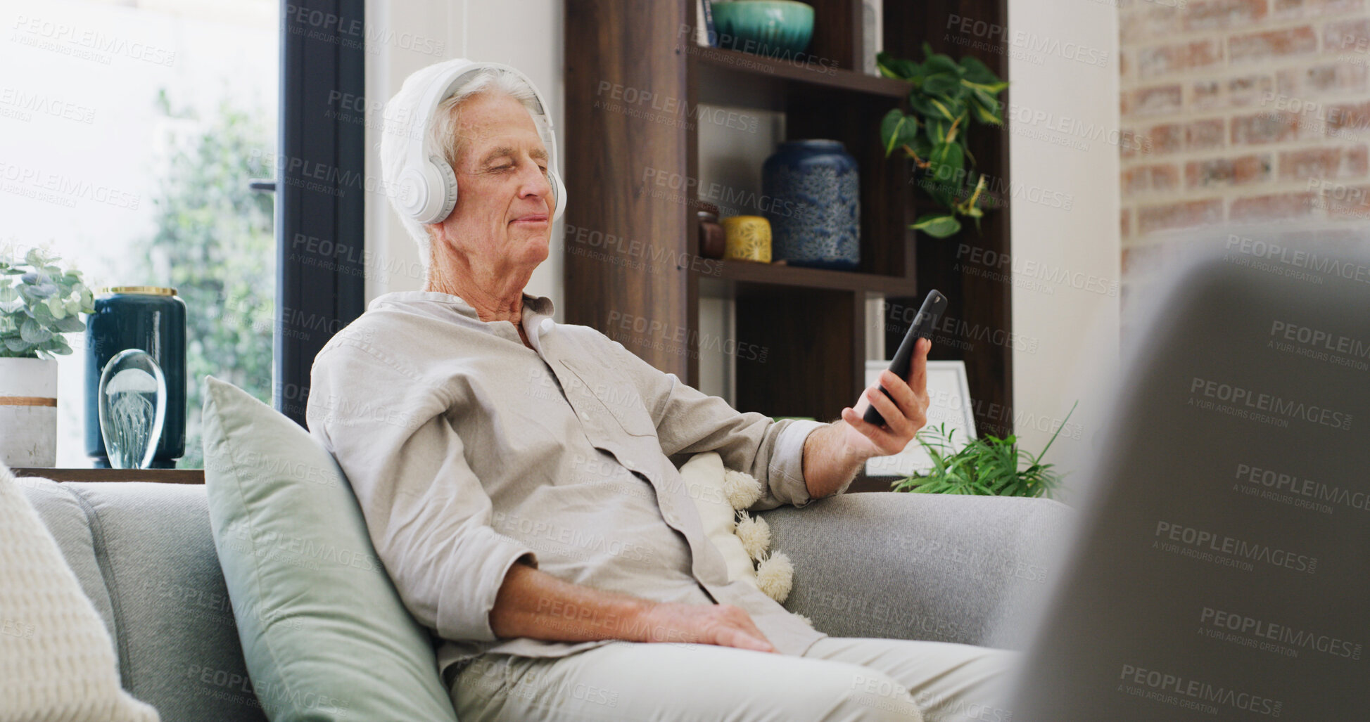 Buy stock photo Music, phone and retirement with old man on sofa in living room of home for streaming subscription. App, headphones and relax with senior person in apartment for audio or sound entertainment