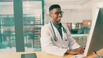 Computer, smile and typing with doctor black man at desk in hospital for results review. Healthcare, medical and online research with medicine professional in office at clinic for agenda or schedule