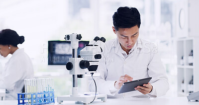 Buy stock photo Man, scientist and typing on tablet in lab for research, medical study and experiment results. Person, coworking and microscope with digital, online checklist and healthcare feedback on vaccine trial