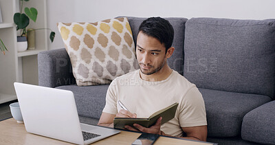 Buy stock photo Man, laptop and writing with book in home for journalism, remote work or business research. Male person, journalist or freelancer checking notes with computer, notebook or diary for schedule or tasks