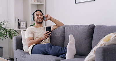 Buy stock photo Smile, phone and music with man on sofa for streaming, radio station and audio playlist. Podcast subscription, headphones and media platform with person in living room of home for connection