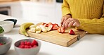 Person, hands and cutting strawberry with board in kitchen for smoothie, nutrition or meal prep. Closeup, health or nutritionist with ingredients or organic fruit for dietary, wellness or vitamins
