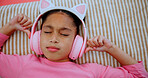 Top view, headphones and kid on bed for audio, streaming service and relax for calm. Music, above and girl in bedroom for song, meditation and child listening to sound to chill for peace in home