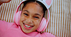Above, headphones and happy kid on bed for audio, streaming service and relax with portrait. Face, top view and girl in bedroom for music, online radio and child listening to sound to chill in home