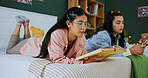 Friends, phone and girls reading book in bedroom for studying, learning or research. Textbook, mobile and women relax on bed for education, test preparation and knowledge with students in home