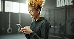 Woman, gym and smile with phone for social media, message or online post and break. Happy african person, sports center and fitness with laugh on internet for funny video, meme or notification