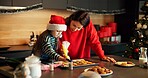 Christmas, mother or child in kitchen with icing, baking help and bonding together in holiday season. Festive, learning or family in house with cookie, connection or sweet treat frosting for Santa.