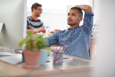 Buy stock photo Serious young multi-ethnic man working at his desk in an open plan work space