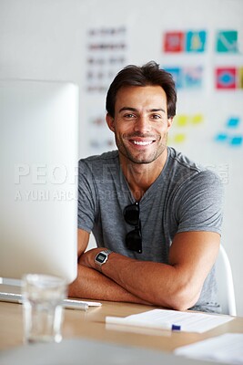 Buy stock photo A handsome young man sitting and smiling in front of his computer