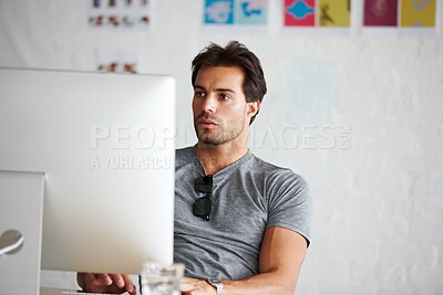 Buy stock photo A handsome young man sitting in front of his computer