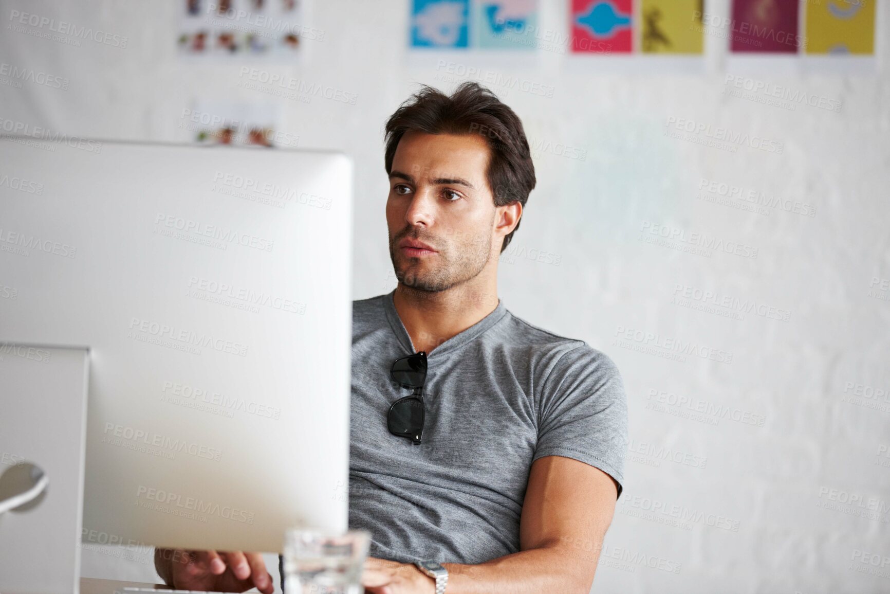Buy stock photo A handsome young man sitting in front of his computer