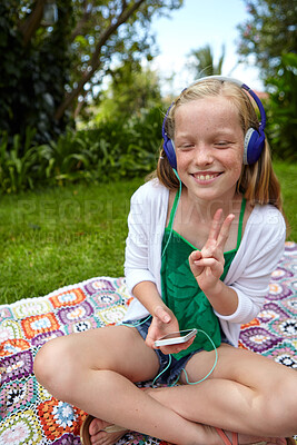 Buy stock photo Smile, child and headphones with phone at park for travel, streaming podcast and summer holiday. Happy, kid and peace sign for listening to music, download playlist and relaxing on grass for vacation