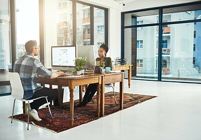 Buy stock photo Full length shot of two businesspeople working on opposite ends of a desk in the office