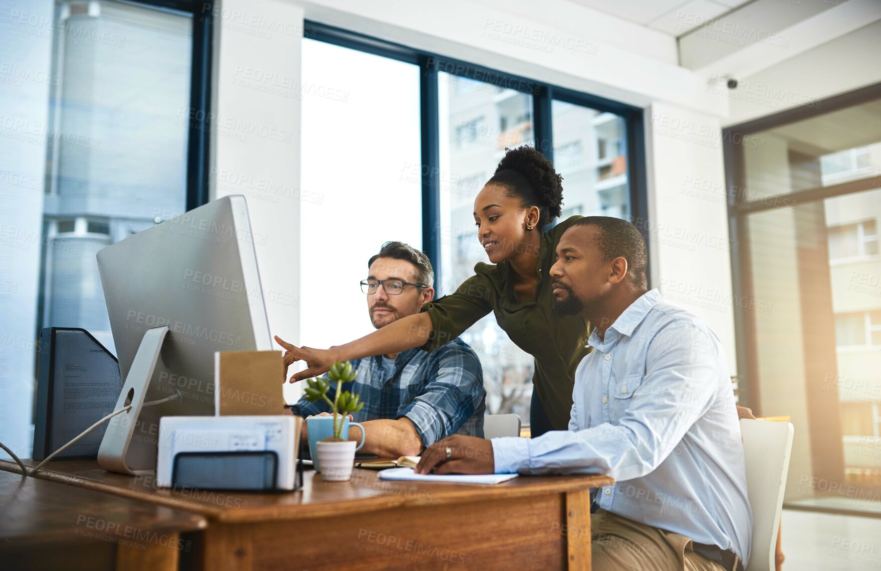 Buy stock photo Cropped shot of three businesspeople working around a computer in the office