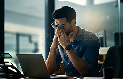 Buy stock photo Shot of a young businessman experiencing stress during a late night at work