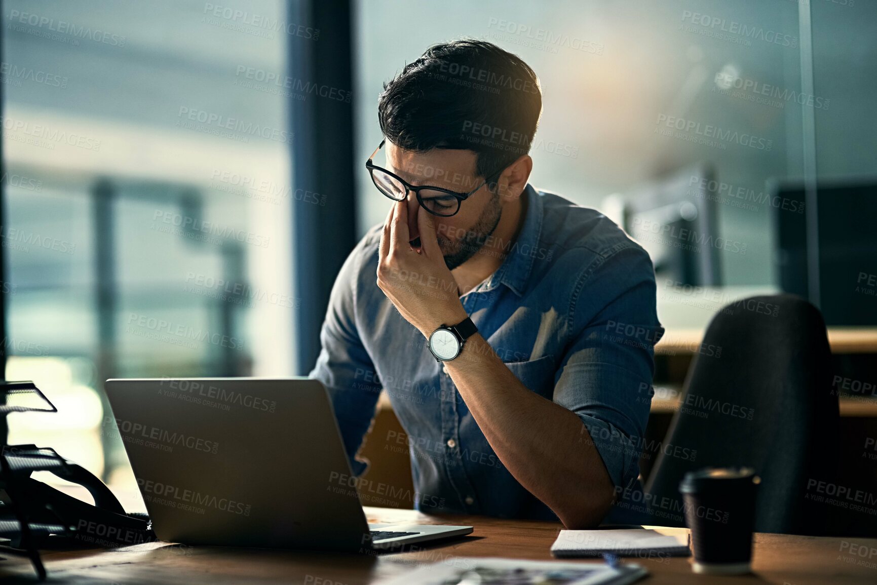 Buy stock photo Shot of a young businessman experiencing stress during a late night at work
