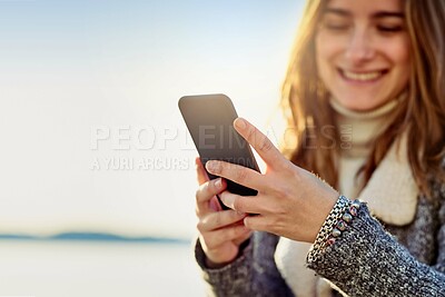 Buy stock photo Happy woman, typing or beach with phone for social media app or communication in nature. Young, female person or traveler with smile on mobile smartphone for online chatting or texting by ocean coast