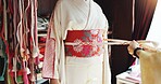 Kimono, belt and help with hands of people at tailor in japan for designer, boutique and fashion. Festive ceremony, culture and traditional clothes with closeup of obi and customer for fabric shop