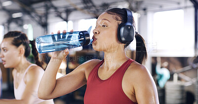 Buy stock photo Drinking water, exercise and woman in gym, hydration and wellness with headphones. Mineral liquid, thirsty and health person in center, training and sound with cold beverage, podcast and radio