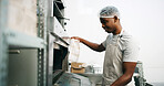 Bakery, kitchen and black man at oven for check, cooking or control temperature for food preparation. Professional chef, safety regulations and person with cloth for inspection, ready time and baking