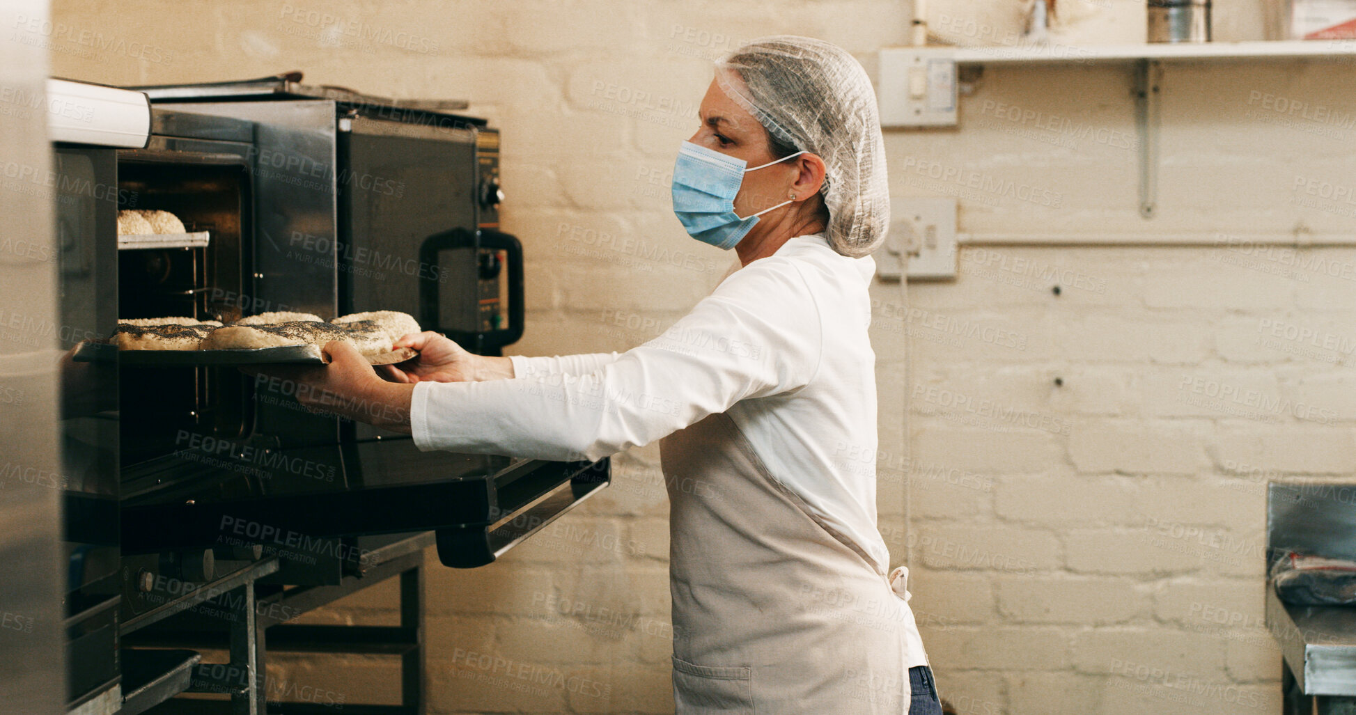 Buy stock photo Bakery, woman and bread in oven in kitchen for breakfast order, baking process or catering service. Hospitality industry, baker or mask in small business for lunch roll preparation or culinary skills